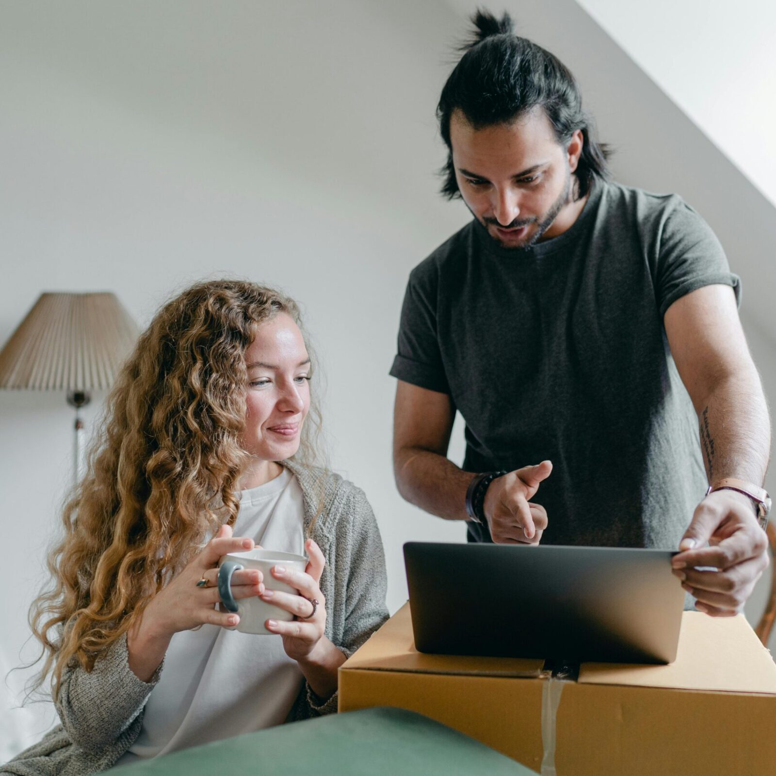 Couple looking at a laptop that's on a cardboard box showing them happy that they have taken Income Protection Insurance